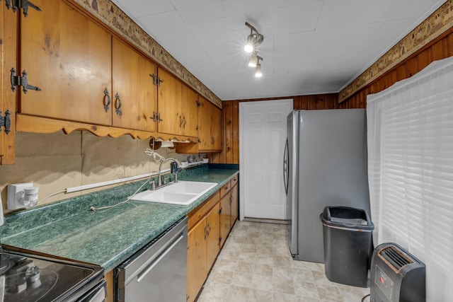 kitchen with stainless steel appliances, dark countertops, brown cabinetry, and a sink