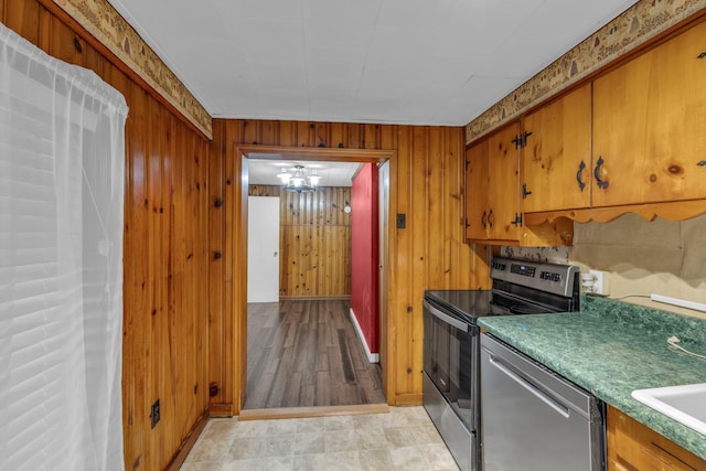 kitchen featuring stainless steel appliances, wooden walls, and brown cabinets