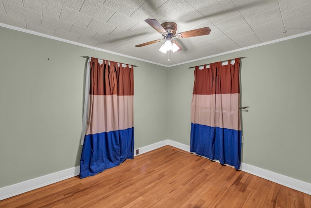 spare room featuring a ceiling fan, crown molding, baseboards, and wood finished floors