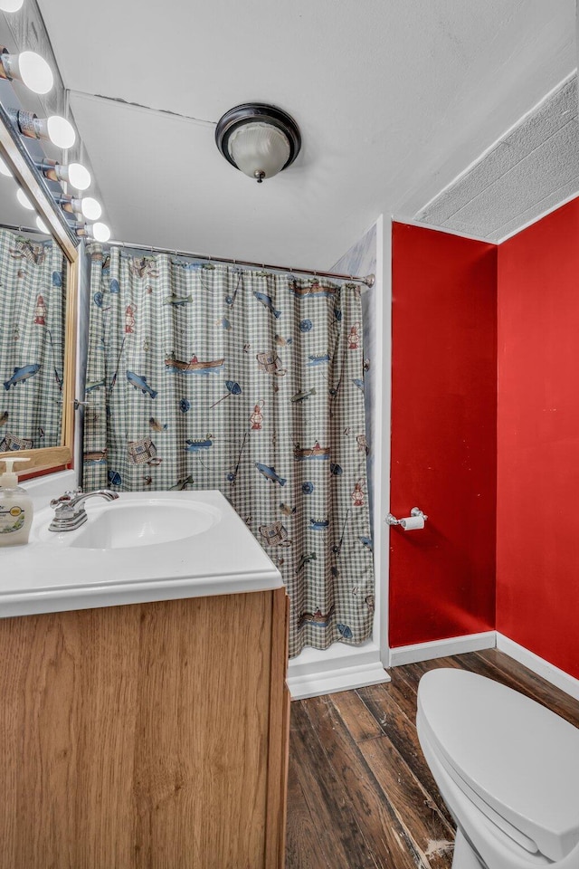 bathroom featuring baseboards, a shower with shower curtain, toilet, wood finished floors, and vanity