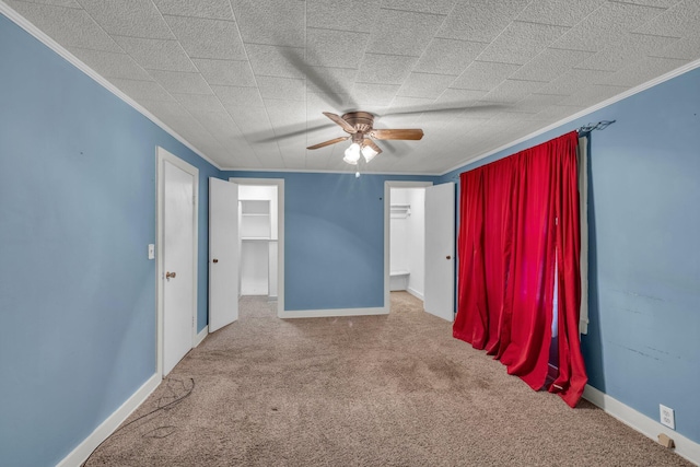 spare room with carpet floors, ornamental molding, baseboards, and a ceiling fan