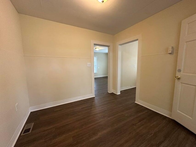 spare room featuring dark wood finished floors, visible vents, and baseboards