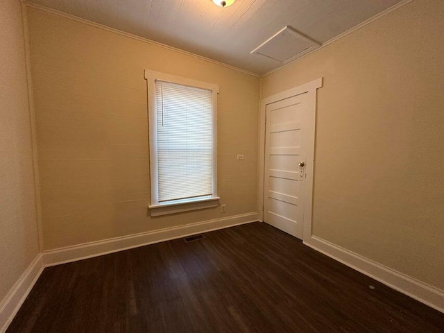 unfurnished room featuring visible vents, baseboards, ornamental molding, dark wood-style floors, and attic access