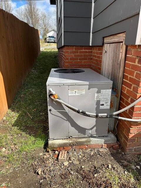 details with fence, central AC unit, and brick siding