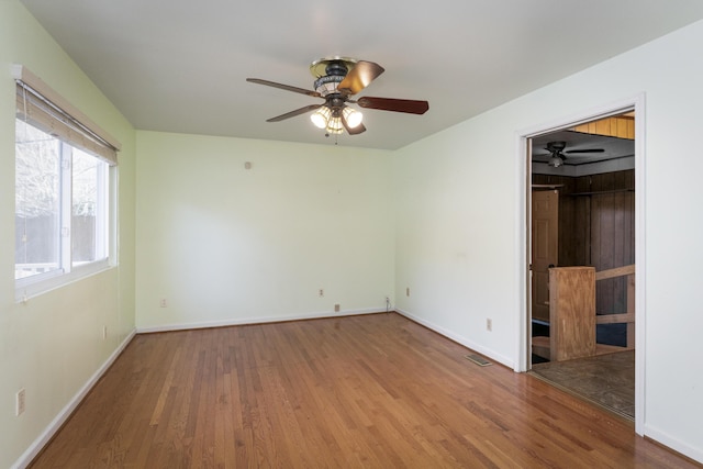 unfurnished bedroom featuring a spacious closet, wood finished floors, baseboards, and a closet