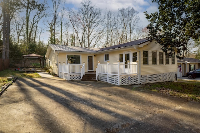 view of front of house featuring a deck, driveway, and metal roof