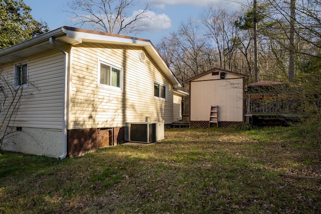 view of side of home featuring a storage unit, an outbuilding, central AC, and a lawn