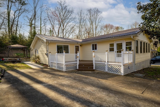 ranch-style home featuring a gazebo, concrete driveway, metal roof, and a deck