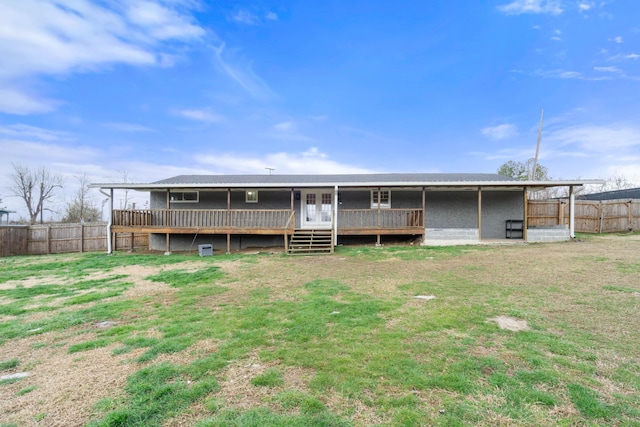 rear view of house with a yard, a wooden deck, and fence