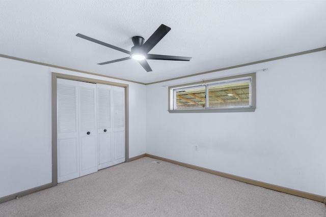 unfurnished bedroom featuring crown molding, baseboards, carpet, a closet, and a textured ceiling