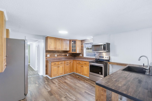 kitchen featuring a sink, dark countertops, appliances with stainless steel finishes, and wood finished floors