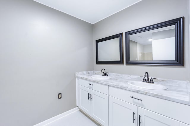 full bath featuring double vanity, baseboards, and a sink