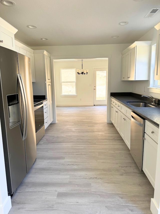 kitchen with stainless steel appliances, a sink, visible vents, white cabinets, and dark countertops