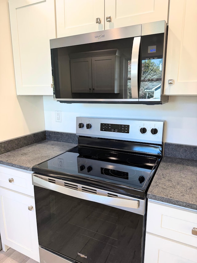 kitchen featuring dark countertops, white cabinets, and stainless steel appliances