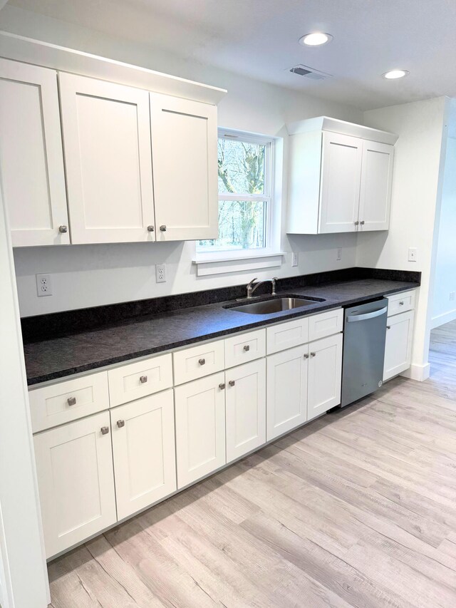 kitchen with light wood finished floors, visible vents, stainless steel dishwasher, white cabinetry, and a sink