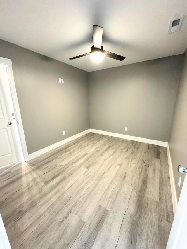 empty room featuring visible vents, ceiling fan, baseboards, and wood finished floors