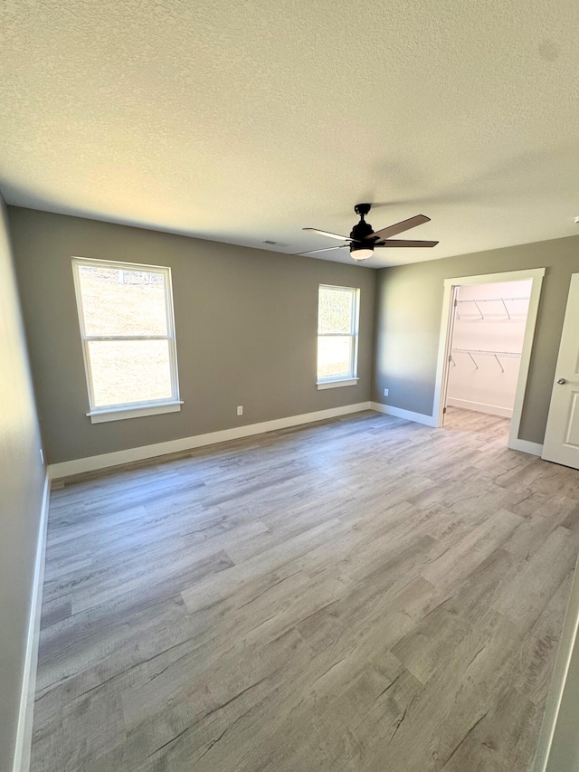 unfurnished room with a textured ceiling, ceiling fan, wood finished floors, and baseboards