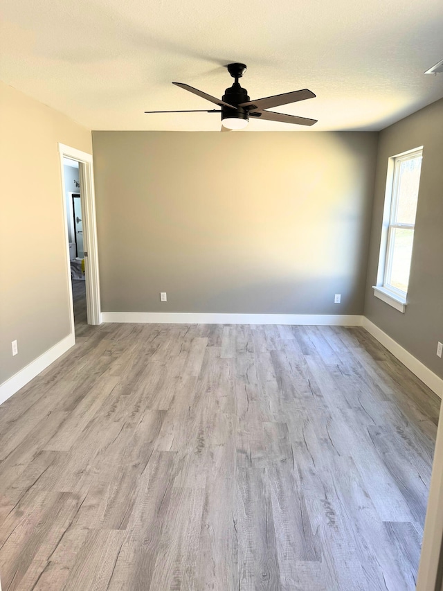 empty room featuring a ceiling fan, a textured ceiling, baseboards, and wood finished floors