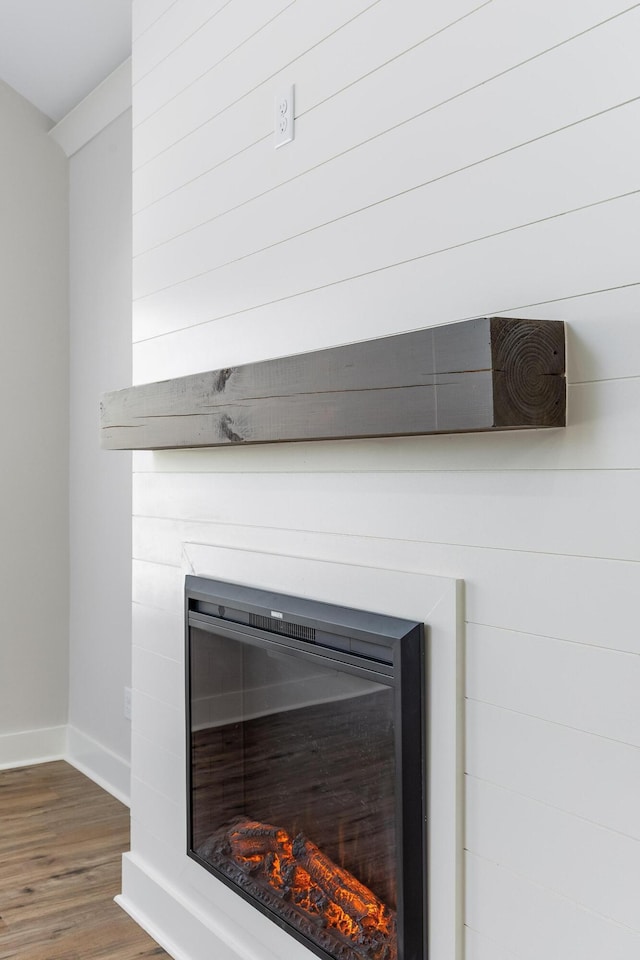 details with baseboards, wood finished floors, and a glass covered fireplace