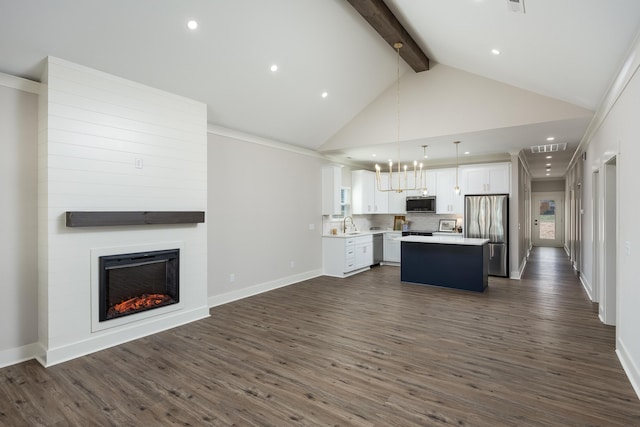 kitchen with white cabinets, open floor plan, beamed ceiling, light countertops, and stainless steel appliances