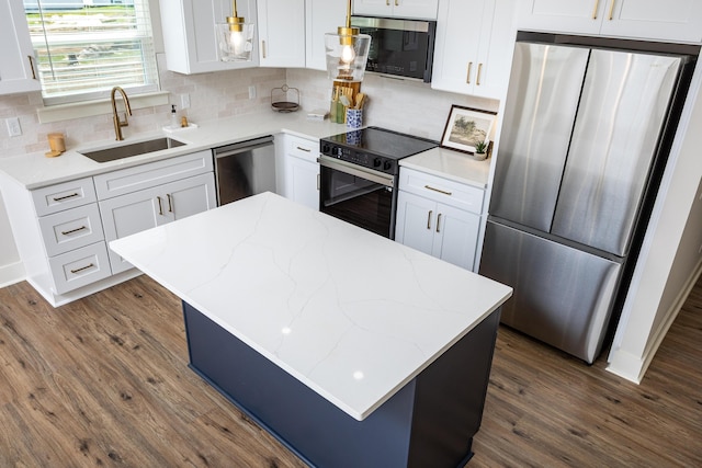 kitchen with appliances with stainless steel finishes, a sink, dark wood finished floors, and white cabinets