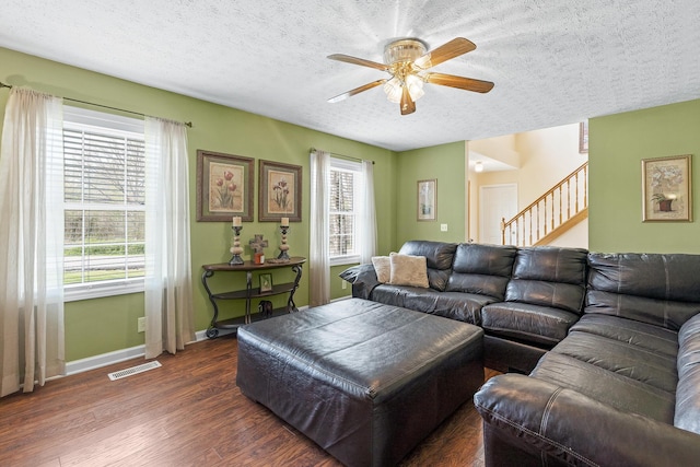 living room with a healthy amount of sunlight, a textured ceiling, visible vents, and dark wood-style flooring