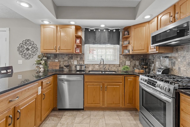 kitchen with dark stone counters, open shelves, appliances with stainless steel finishes, and a sink