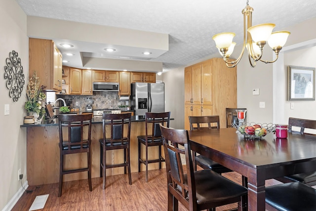 dining space featuring a textured ceiling, wood finished floors, visible vents, and an inviting chandelier