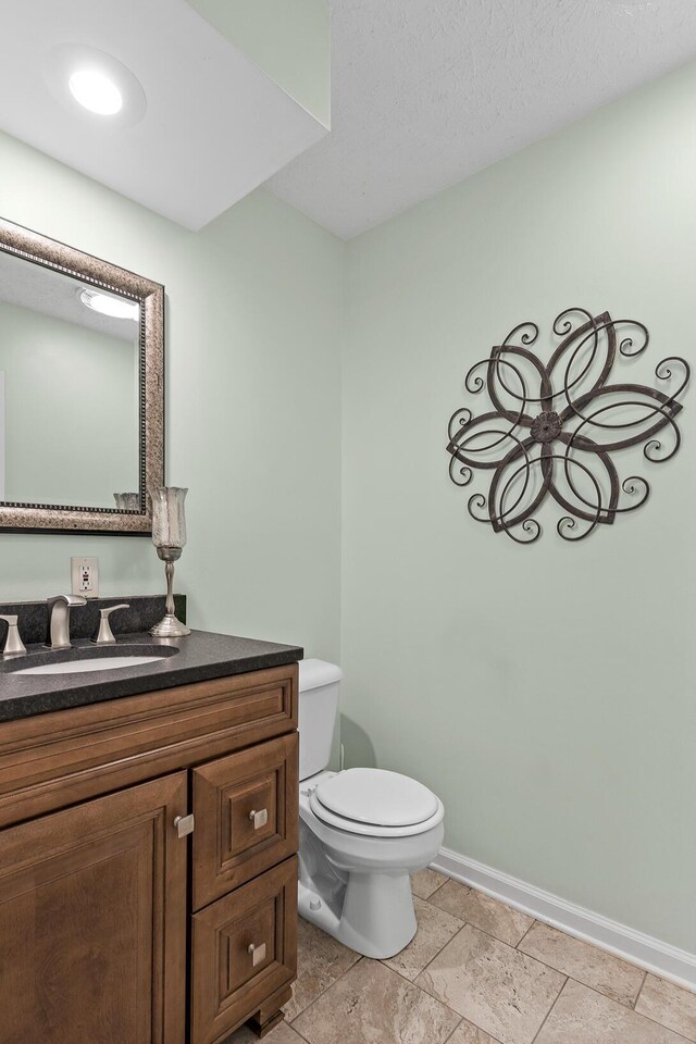 bathroom featuring baseboards, vanity, and toilet