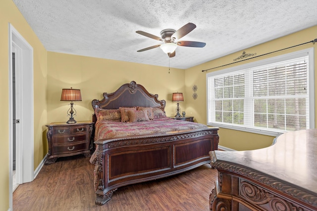 bedroom with ceiling fan, baseboards, dark wood finished floors, and a textured ceiling