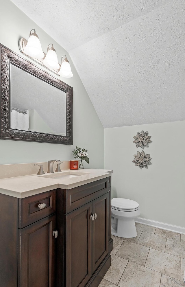 bathroom with baseboards, toilet, vaulted ceiling, a textured ceiling, and vanity