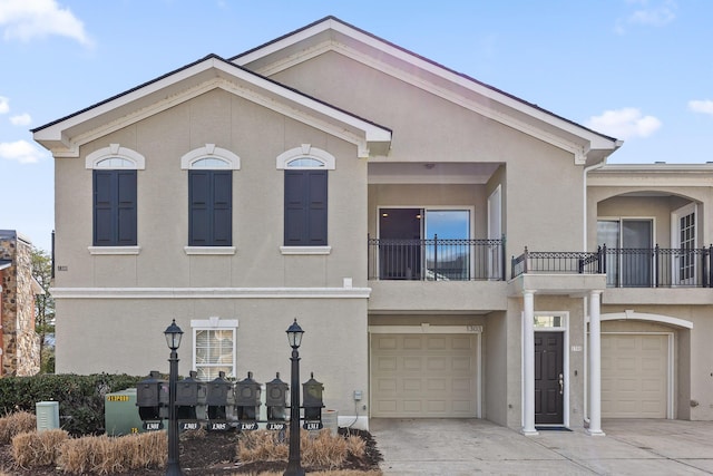 view of front of home with a balcony, an attached garage, driveway, and stucco siding