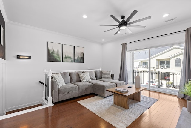 living area featuring dark wood finished floors, visible vents, ornamental molding, and a ceiling fan