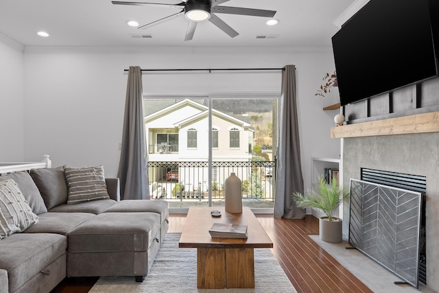 living area with visible vents, wood finished floors, a ceiling fan, and ornamental molding