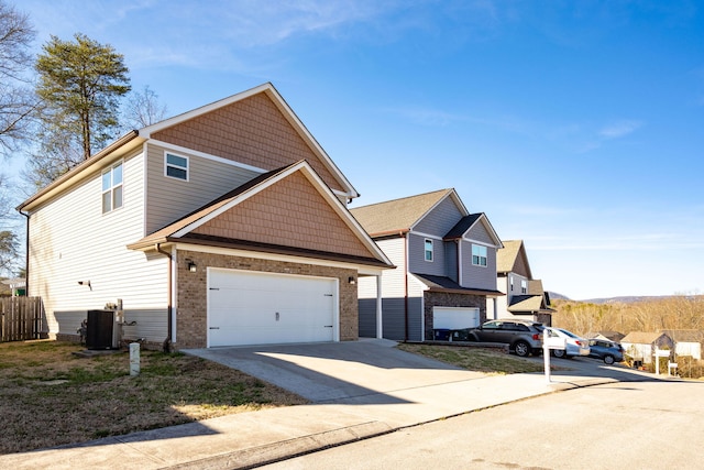 view of front facade featuring brick siding, fence, concrete driveway, central AC, and a garage