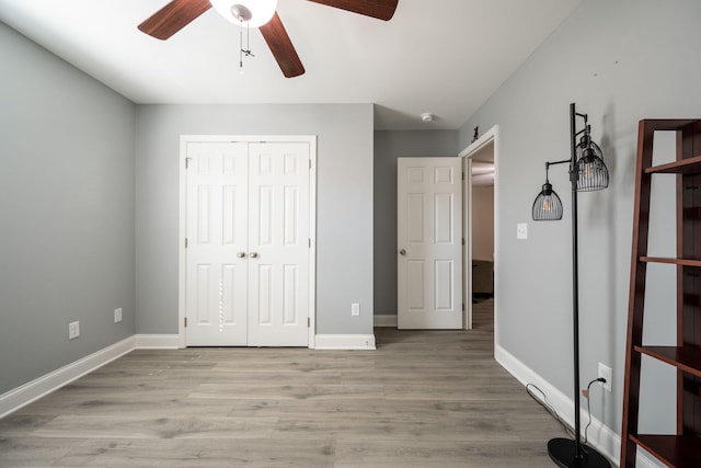 unfurnished bedroom with a closet, baseboards, ceiling fan, and light wood finished floors