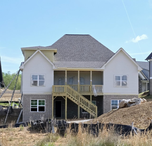 back of house featuring roof with shingles, stairway, and brick siding