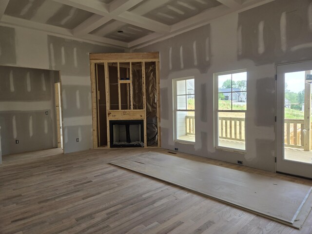 unfurnished living room featuring beam ceiling, coffered ceiling, wood finished floors, and a fireplace