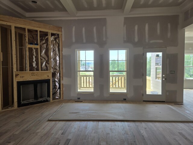 unfurnished living room with a glass covered fireplace, wood finished floors, and beamed ceiling