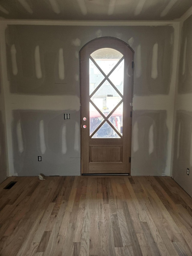 doorway to outside featuring visible vents, arched walkways, and wood finished floors
