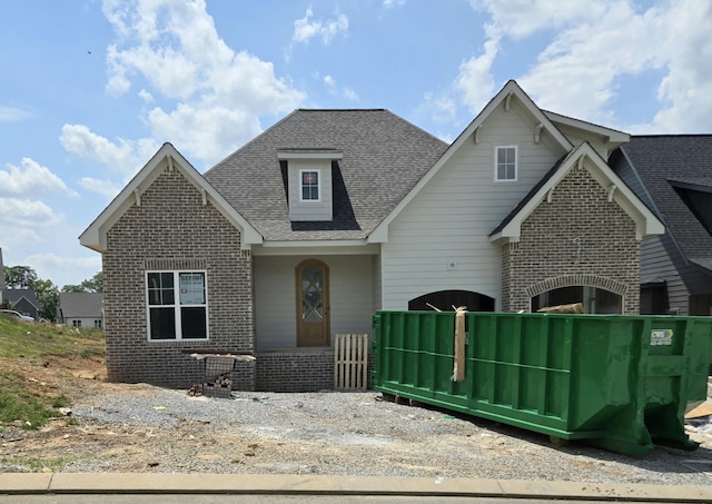 craftsman inspired home with roof with shingles and brick siding