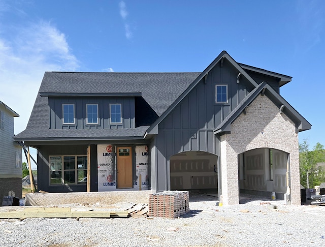 view of front of house featuring a shingled roof, a garage, board and batten siding, covered porch, and driveway
