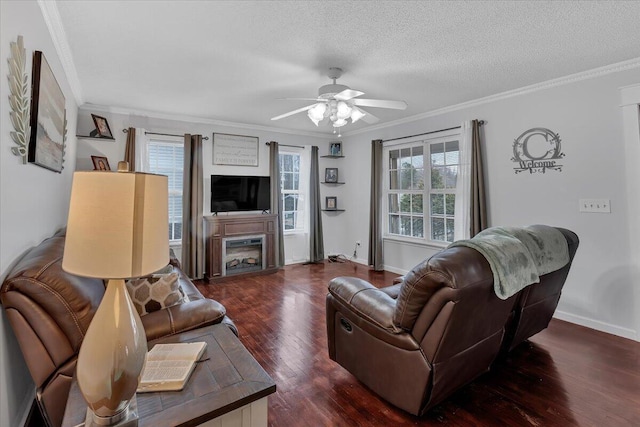 living area with a textured ceiling, a fireplace, wood finished floors, a ceiling fan, and crown molding