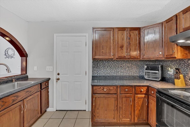 kitchen featuring tasteful backsplash, brown cabinetry, light tile patterned flooring, and a sink