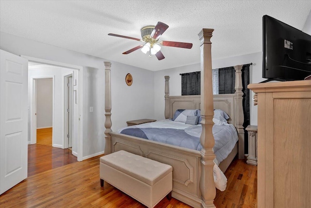 bedroom featuring baseboards, ceiling fan, light wood-style flooring, and a textured ceiling