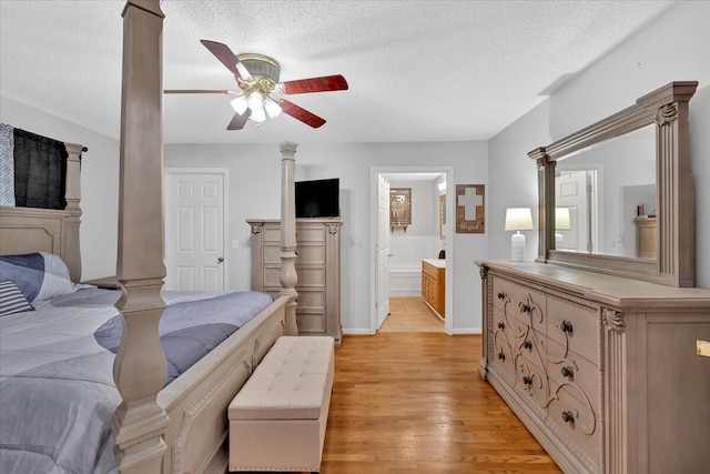 bedroom featuring a textured ceiling, connected bathroom, a ceiling fan, light wood finished floors, and ornate columns