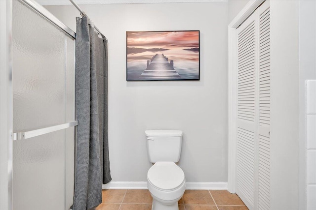 full bath featuring curtained shower, a closet, toilet, baseboards, and tile patterned floors