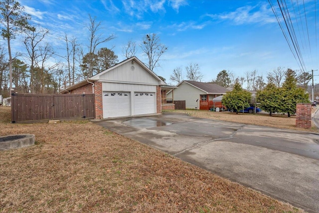 view of front of house with brick siding, concrete driveway, a front yard, fence, and a garage