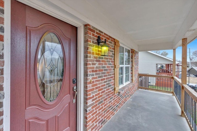 doorway to property with a balcony and brick siding