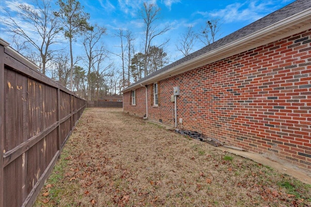 view of side of property with a yard, a fenced backyard, and brick siding